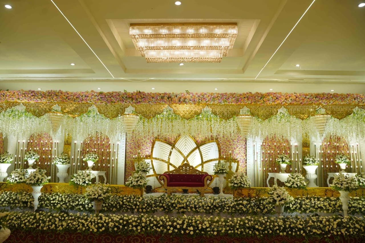 Golden ballroom stage covered in flowers with a traditional throne