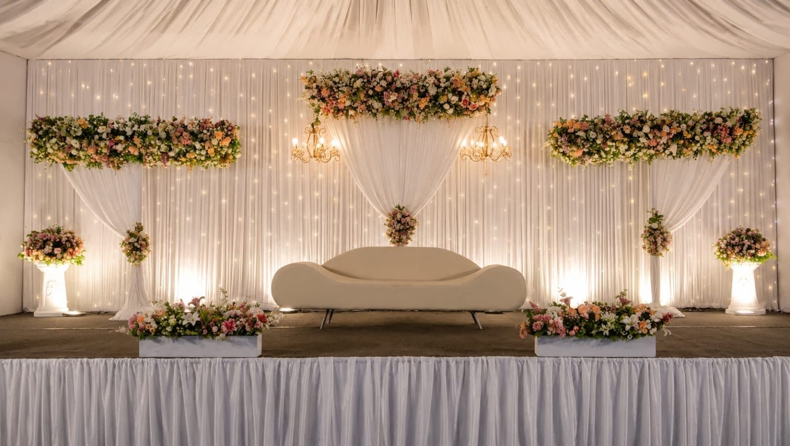 Outdoor stage with white drapes, fairy-light curtain and floral frames