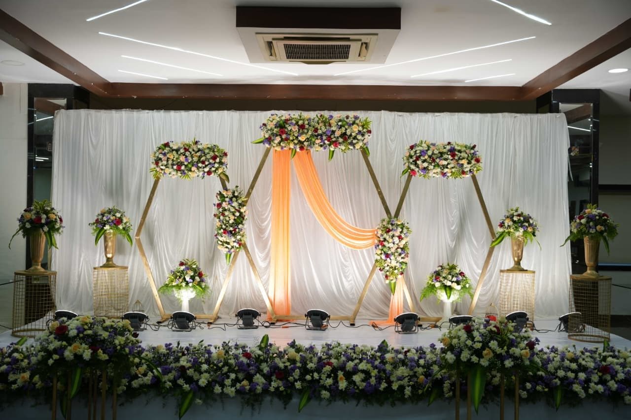 Indoor wedding stage with peach drapes and white florals
